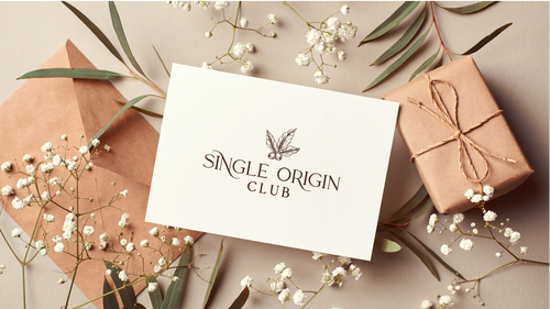 Single Origin Club card with gift box and decorative elements on a neutral background