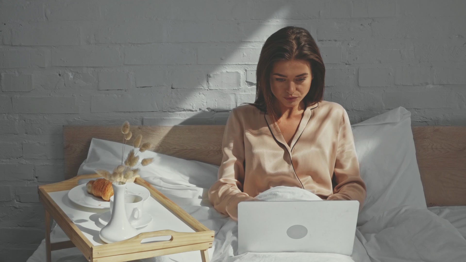 Woman drinking a cup of coffee in her bed while she works. Single Origin Club.